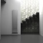 Radiator mounted on white wall with textured black and white brick wall background, modern minimalist interior design.