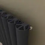 Radiator with modern black design and ventilation grille for heating system.