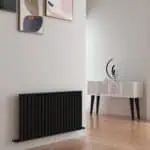 Modern black radiator and stylish white sideboard with decorative objects in contemporary living space.