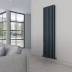 Contemporary black vertical radiator in modern living room with large window and gray sofa.