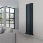 Contemporary black vertical radiator in modern living room with large window and gray sofa.