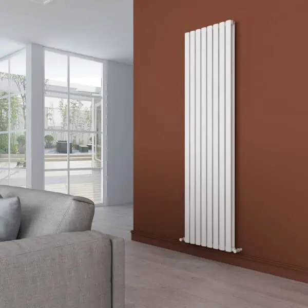 Modern white vertical radiator in a contemporary living room with a brown accent wall and large glass windows, stylish heating solution.