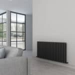 Modern black radiator installation inside a contemporary living room with large glass doors.
