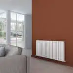 Modern living room with white radiator on terracotta accent wall and large windows with garden view.