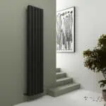 Black modern vertical radiator in minimalist interior.