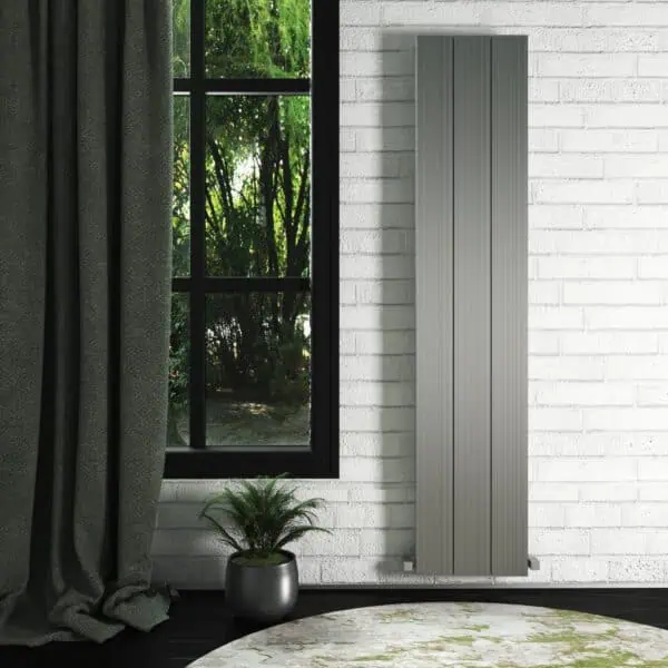 Modern vertical grey radiator in a minimalist interior setting with a large window and greenery outside.