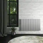 Modern white wall-mounted electric radiator in a stylish interior with a window overlooking greenery.