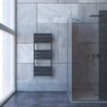 Modern bathroom with sleek gray towel radiator and glass shower partition, minimalist design, tiled walls and floors.