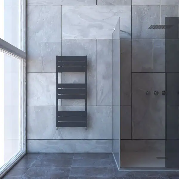 Modern bathroom with sleek gray towel radiator and glass shower partition, minimalist design, tiled walls and floors.
