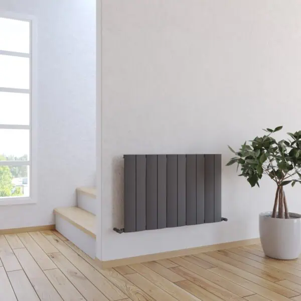 Modern black wall radiator in bright minimalist interior with potted plant and wooden staircase.