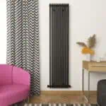 Stylish black vertical radiator in modern living room with patterned curtains and pink sofa.