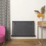 Radiator heating panel in modern interior living space with decorative vase and flowers.