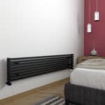 Black modern radiator, sleek wall-mounted heating panel in contemporary bedroom decor.