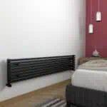 Black modern radiator, sleek wall-mounted heating panel in contemporary bedroom decor.