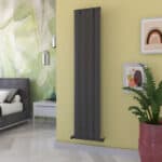 Sleek black vertical electric radiator heater in modern bedroom interior.