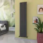 Sleek black vertical electric radiator heater in modern bedroom interior.