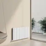 Contemporary white panel radiator installed in modern apartment with large window and city view, ideal for home heating.