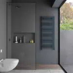 Modern gray bathroom with walk-in shower, wall-mounted toilet, and blue heated towel rail. Natural light highlights sleek design.