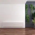 Modern interior with sleek white radiator and green plants, stylish home decor and wood flooring.