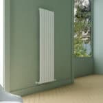 Modern white vertical radiator in a cozy green-walled room with a large window.