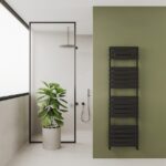 Black heated towel rail radiator in modern bathroom with green accent wall and indoor plant, style and heating solution for home bathrooms, Poshrads.