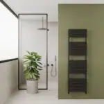 Black heated towel rail radiator in modern bathroom with green accent wall and indoor plant, style and heating solution for home bathrooms, Poshrads.