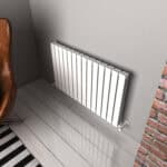 Radiator heating system with modern white panel radiator in interior space.