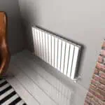 Radiator heating system with modern white panel radiator in interior space.