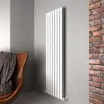 Modern white vertical radiator mounted on a gray wall in a contemporary interior.