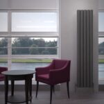 Modern office space with large windows, purple armchairs, and a sleek vertical radiator for stylish heating.