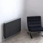 Radiator and Modern Black Chair in Minimalist Interior.