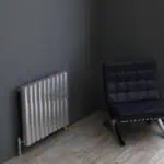 Radiator and modern black lounge chair in minimalistic room.