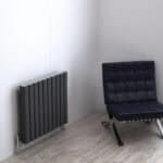 Radiator and black chair in modern interior space, minimalistic design, home decor, cozy living area.