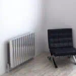 Radiator and modern black lounge chair in minimalistic interior setting, cozy and stylish home decor.