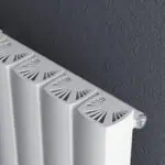 Modern white radiator with decorative vents in a contemporary indoor setting.