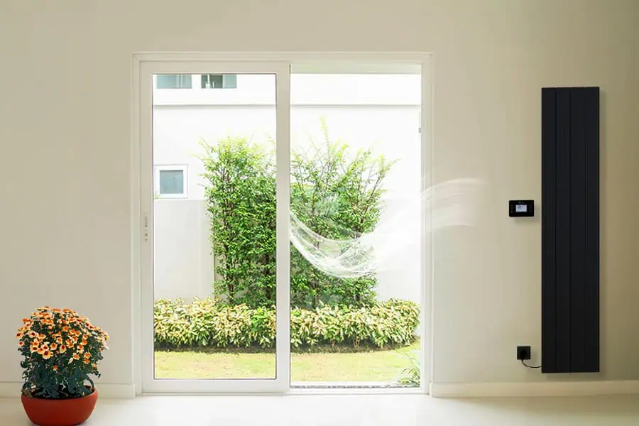 Sliding glass door with modern black radiator and plant in pot, overlooking a garden.