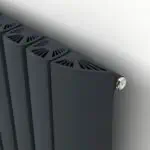 Modern black radiator with vented top panel, wall-mounted heating unit, close-up view of home heating system.