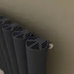 Black modern radiator with innovative ventilation design in a cozy home setting.