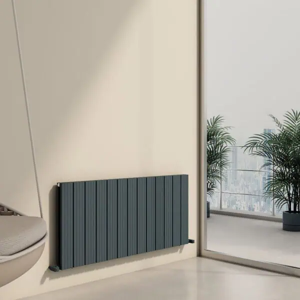 Radiator heater mounted on a wall in a modern office space with large windows and potted plants.