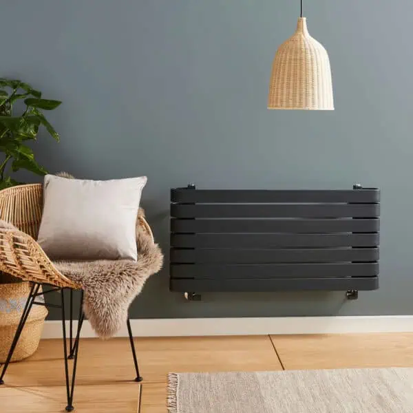 Modern black radiator in stylish living room, with cozy armchair and pendant light, ideal for contemporary home heating.