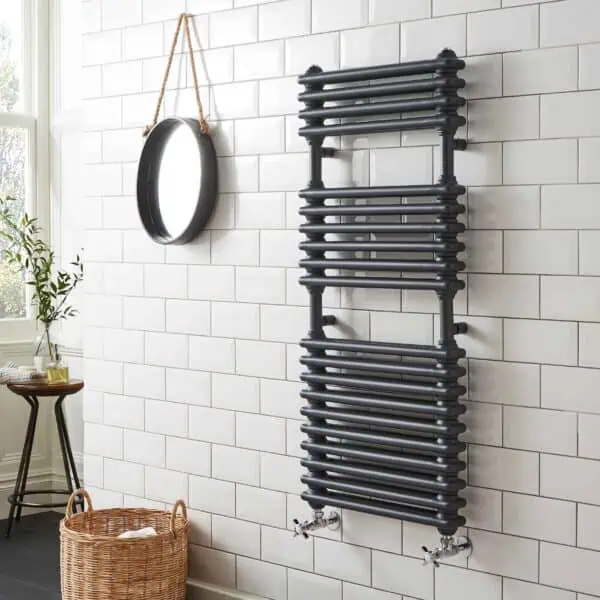 Radiator towel rail in bathroom with white subway tiles and natural wicker basket, modern heating element.