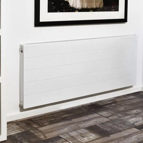 Radiator cover on a white wall with decorative items and wooden flooring.