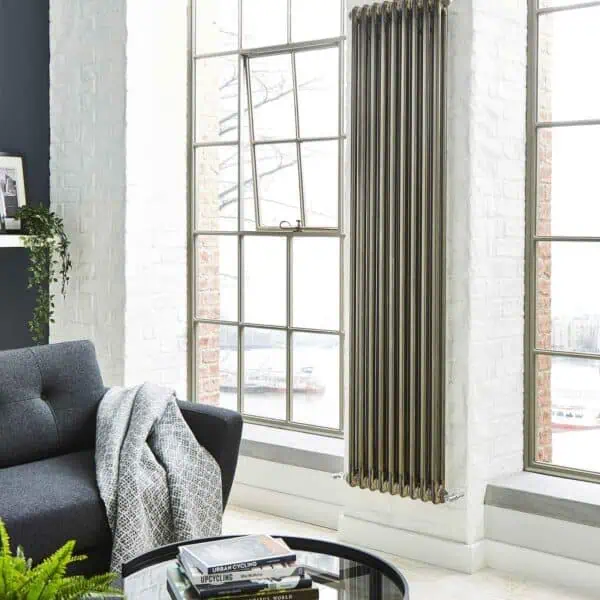 Modern vertical radiator in industrial style living room with large windows and white brick wall.