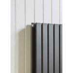 Modern black radiator mounted on white panelled wall for home heating.
