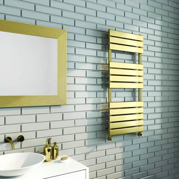 Polished gold towel radiator and modern bathroom decor with white brick wall and vanity, elegant bathroom design.