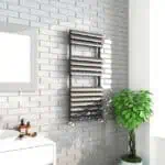 Polished stainless steel towel radiator in modern bathroom design.