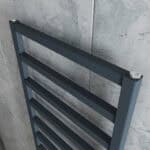 Aluminum towel warmer radiator close-up mounted on a tiled wall.