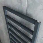 Aluminum towel warmer radiator close-up mounted on a tiled wall.